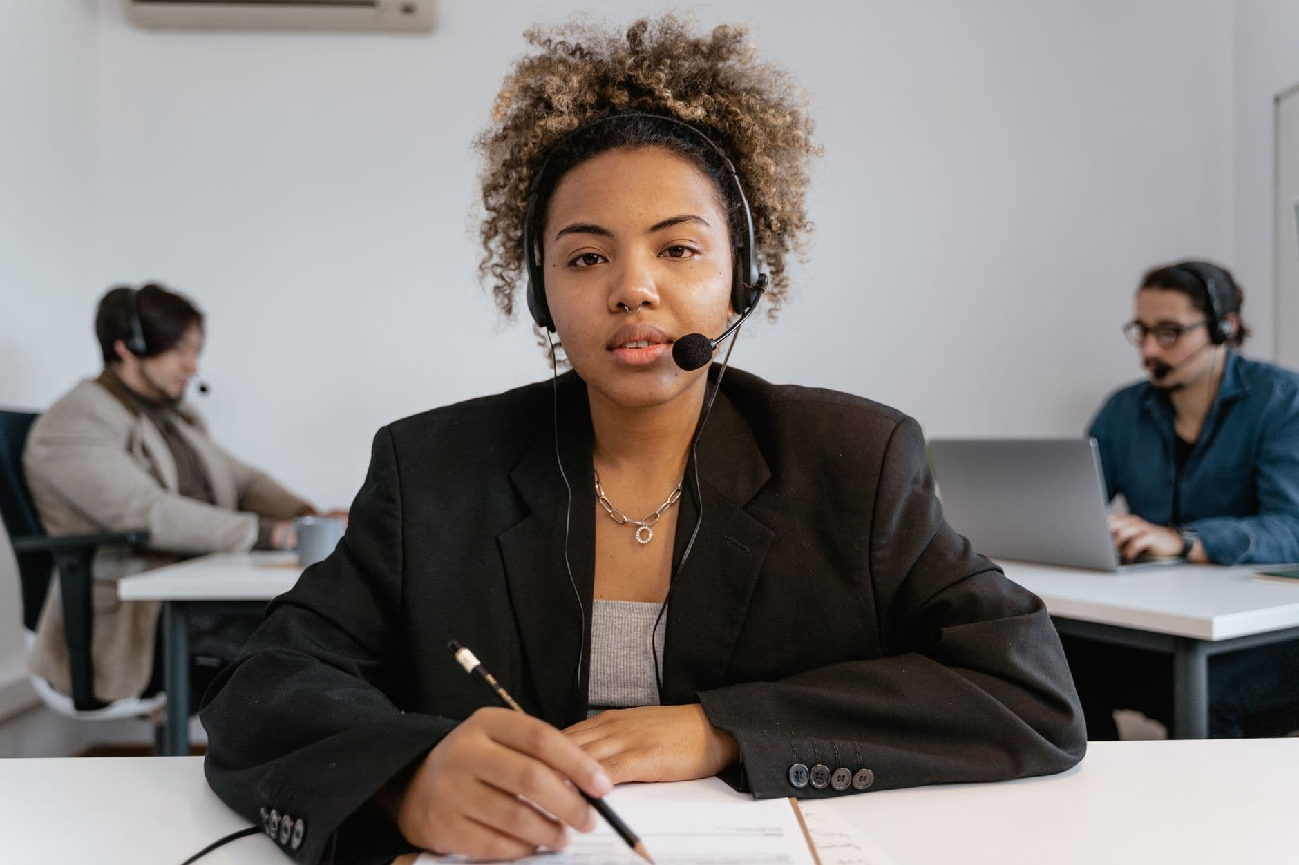 Confident call center agent assisting customers in an office environment.