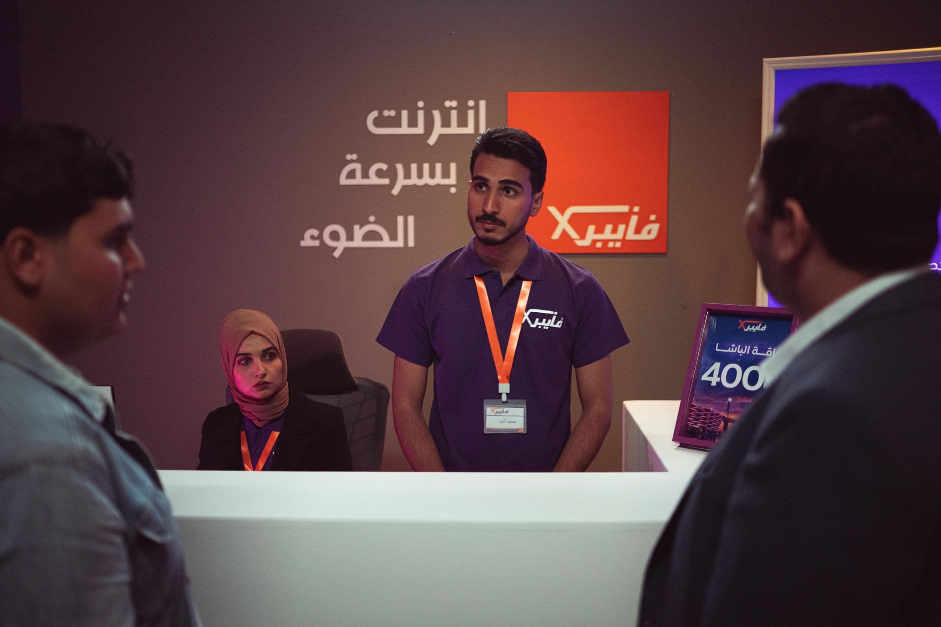 People interacting at a tech company front desk with modern design and branding.
